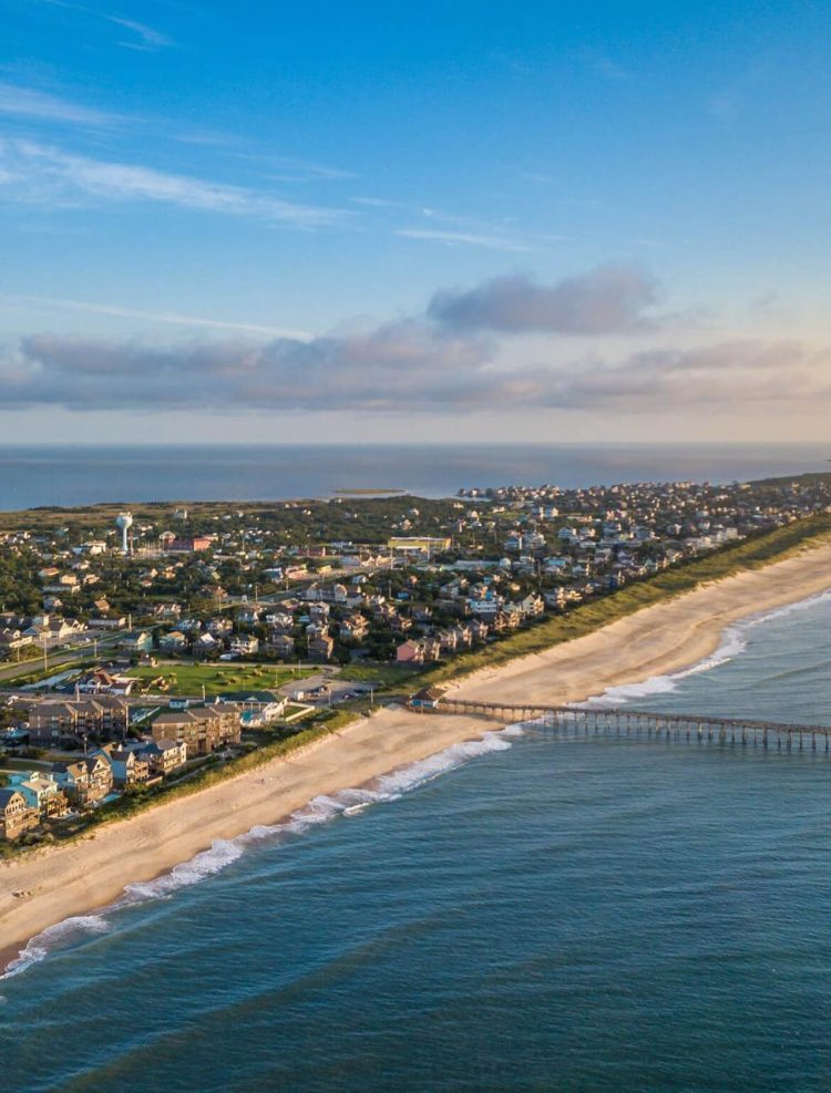 Experiences 1 Aerial view of the coastline, highlighting the sea, sandy beaches, sky, and buildings, creating a beautiful and expansive landscape.