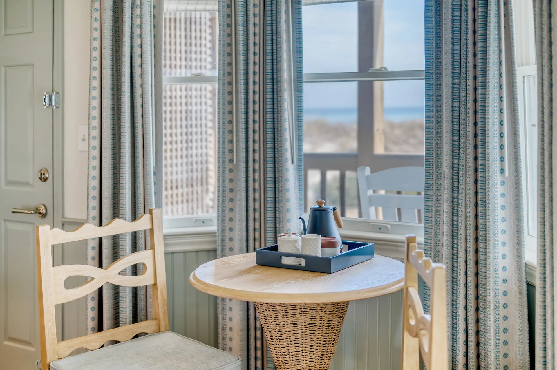 Accommodations 11 Tea set in a cozy corner of the Sanderling room, featuring a small table and two wooden chairs.
