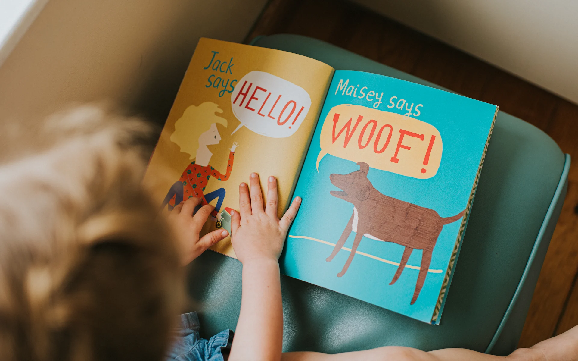 Child reading a book at The Sanderling Hotel's Morning Storytime event