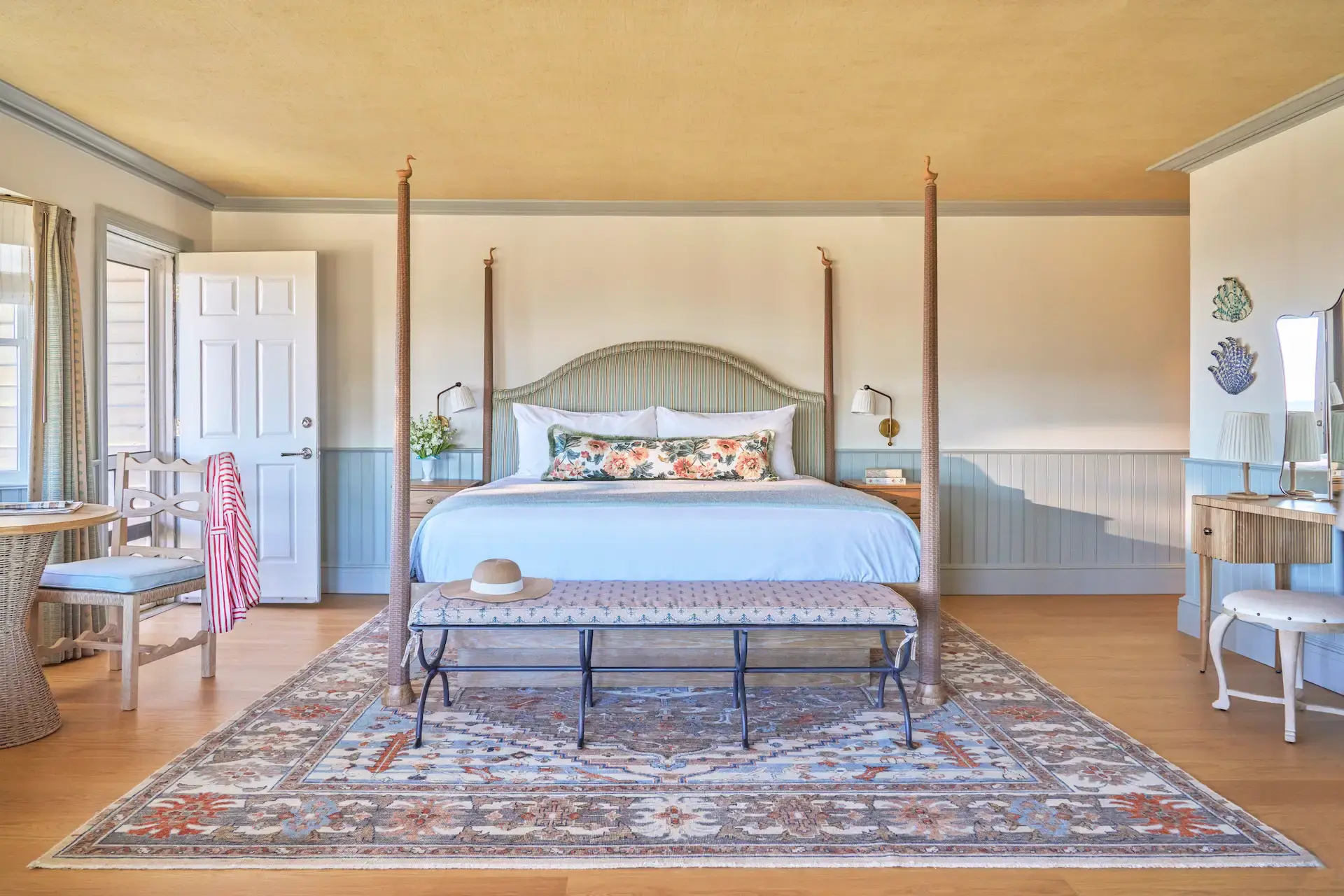 Accommodations 12 Room at The Sanderling Resort decorated in soft pastel blue tones with geometric rugs and wooden furniture.